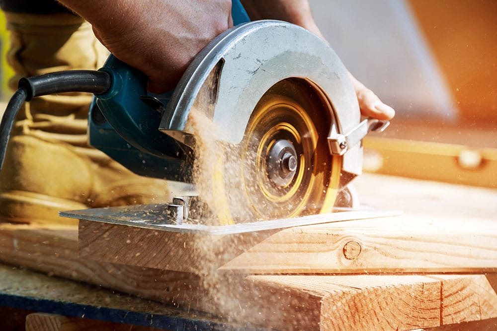 building contractor worker using hand-held worm drive circular saw cut boards